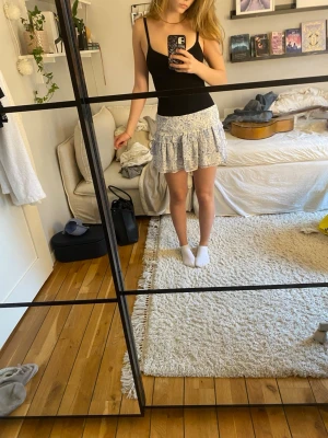 Superfin vit kjol med blåa blomdetaljer - Söpersöt, kort kjol med volanger och blomdetaljer. Köpt från ginatricot. 