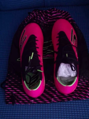 Rosa fotbollsskor från Skechers Elite  - Säljer ett par grymma fotbollsskor från Skechers i en riktigt snygg rosa färg med svarta och neongröna detaljer. Skorna har dobbar för bra grepp på planen och en modern, strömlinjeformad design. Perfekta för dig som vill sticka ut på fotbollsplanen!