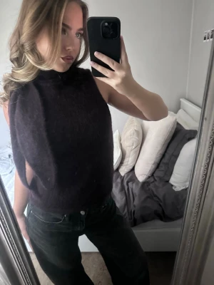 Svart ärmlös stickad tröja - Säljer en lila, ärmlös stickad tröja med hög hals. Material: 33% polyamid, 32% mohair, 32% ull samt 3% elastan. Använd 2 gånger, ny skick!💜