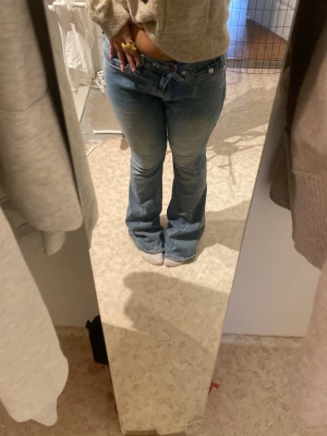 Blå bootcut jeans från True Religion - Säljer ett par blå bootcut jeans från True Religion med klassisk fickdetalj och logga bak. Jeansen har låg midja, ljus tvätt och snygga kontrastsömmar. Perfekta för dig som gillar en avslappnad men trendig look.