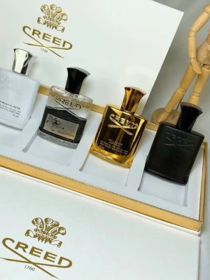 Creed parfymset med fyra flaskor - Lyxigt parfymset från Creed med fyra olika flaskor i vitt, transparent, guld och svart. Flaskorna har elegant design med metalliska lock och Creed-loggan på framsidan. Perfekt presentförpackning för dig som vill testa flera exklusiva dofter.
