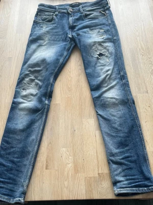 Blåa slitna replay jeans - Ett par slitna snygga jeans från replay i storlek 32.