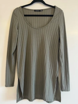 Ribbad långärmad topp från Boohoo - Snygg ribbad topp från Boohoo. Modellen har långa ärmar, rund halsringning och slitsar i sidorna för en relaxed vibe. Perfekt att styla med jeans eller kjol för en clean look.