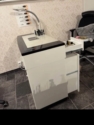 Nagelbord med förvaring och lampa - Snyggt vitt nagelbord med svart kant, inbyggd förvaring och utdragbara lådor. Bordet har en inbyggd utsugningsfläkt och en flexibel LED-lampa. Perfekt för nagelstudio eller hemmabruk. Materialet är robust och lätt att rengöra.