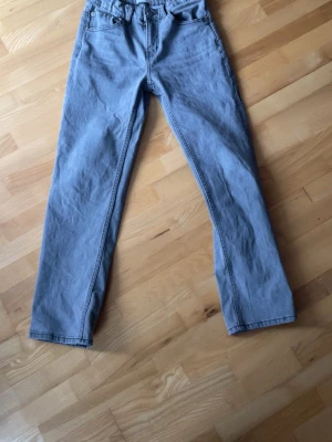 Ljusblå raka jeans - Säljer ett par ljusblå jeans med rak passform och klassisk femficksdesign. Jeansen har normal midja och stängs med dragkedja och knapp. Tillverkade i denim, perfekta för en avslappnad stil.