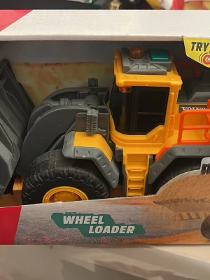 Volvo hjullastare leksak Dickie Toys - Säljer en Volvo hjullastare i plast från Dickie Toys. Leksaken är gul, svart och grå med detaljer i orange och har funktioner med ljus och ljud. Perfekt för dig som gillar byggfordon och maskiner. Kommer i originalförpackning.