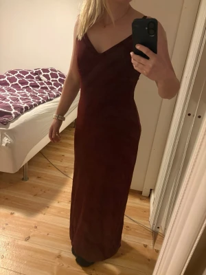 KAFFE Vinröd långklänning i storlek S - Säljer en elegant vinröd långklänning med v-ringning och smala axelband. Klänningen har en snygg slits på sidan som ger en extra touch. Perfekt för dig som vill ha en stilren och feminin look.