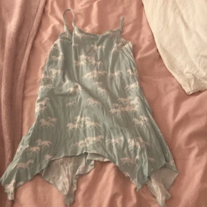 Ljusblå nattlinne med hästmönster H&M - Söt ljusblått nattlinne från H&M med vita hästar som mönster. Nattlinnet har tunna axelband, asymmetrisk nederkant och är tillverkad i ett tunt, luftigt material som passar perfekt till varma dagar.