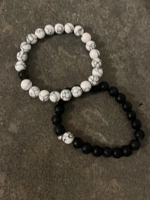 Svart och vitt pärlarmbandsset - Två elastiska armband med runda pärlor, ett i svart och ett i vitt med grå marmorering. Armbanden har en modern och minimalistisk stil och passar perfekt att bära tillsammans eller var för sig. 1 för 99 eller båda för 140 kr