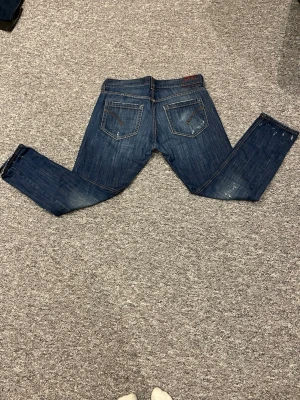 Mörkblå dondup jeans med slitningar - Säljer ett par mörkblå jeans med snygga slitningar och tvättade detaljer. I storlek så står det size 36 men tror inte det stämmer så följ bilderna L98cm och W45cm 