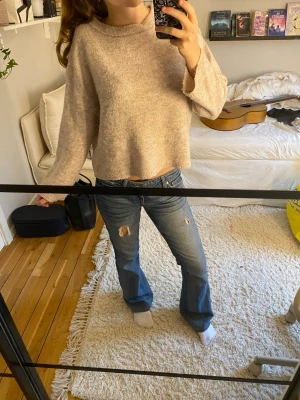 Beige, stickad tröja  - Mysig beige stickad tröja med croppad passform och vida ärmar. Tröjan har en enkel design med ribbad halsringning och är tillverkad i ett mjukt material som känns skönt mot huden. 