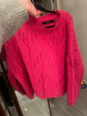 Rosa stickad tröja med hålmönster - Säljer en snygg rosa stickad tröja med hålmönster och rund hals. Tröjan har en oversized passform och långa ärmar. Perfekt för dig som vill ha något både mysigt och trendigt i garderoben.