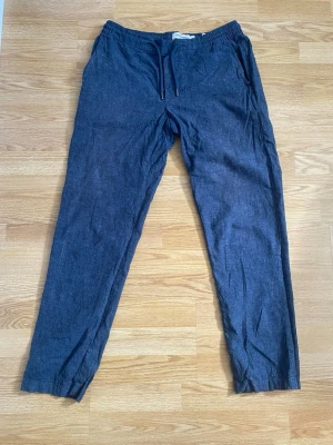 Mörkblå linnebyxor - Snygga mörkblå linnebyxor från Dressmann med avslappnad passform och elastisk midja. Storlek M men passar även S. Byxorna har sidfickor och är tillverkade i ett lätt och luftigt linnematerial, perfekta för en chill och stilren look.