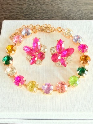Färgglatt smyckeset  ”festival”  - Armband med 8mm stora stenar i olika färger som rosa, lila, grön, gul. Stenarna sitter i guldfärgad metall och armbandet har ett justerbart spänne. Örhänge med matchande färger. Perfekt för dig som gillar färg och vill sticka ut.