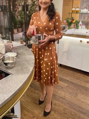 Milan Dress från Jessica Frej  - Snygg brun prickig  omlottklänning, Milano dress,  från Jessica Frej . Klänningen har trekvartsärmar, v-ringning och markerad midja. Kjolen är utsvängd och materialet är mjukt och stretchigt, perfekt för en trendig look.