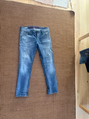 Blå slitna jeans med straight/smal passform. Sitter som 30/32 - Säljer ett par blå jeans med slitningar och tvättade detaljer. Jeansen har smal passform och klassisk femficksdesign. Perfekta för dig som gillar en avslappnad och trendig stil. Pris går att diskutera vid snabb affär😁