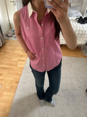 Rosa-randig ärmlös Ralph Lauren Sport  - Superfin ärmlös skjorta från Ralph Lauren Sport i rosa och vitt. Perfekt till sommaren eller under en stickad tröja! Inga spår av användning. Storlek: märkt US 10, men passar perfekt som en medium (se bild för passform på mig som är S). 100% bomull. 