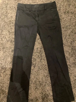 Svarta chinos från Zara Basic - Snygga svarta chinos från Zara Basic med klassisk rak passform och bälteshällor. Byxorna har diskreta fickor och är tillverkade i ett mjukt bomullsmaterial som känns bekvämt hela dagen. Perfekta för en stilren look.