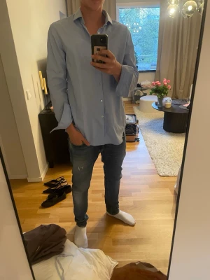  Ljusblå/vit Hugo boss skjorta - Säljer en stilren ljusblå/vit prickig skjorta med klassisk krage och knäppning framtill. Skjortan har lång ärm och rak passform, perfekt till jeans eller chinos. Enkel och tidlös design som funkar till många olika stilar. Är storlek 43 som jag skulle jämföra med L