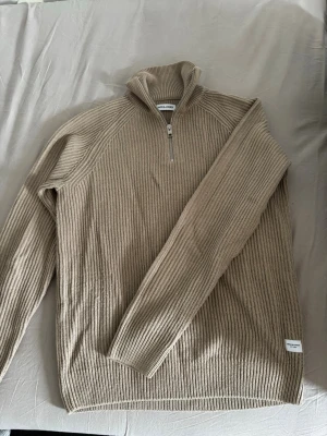 Beige stickad half-zip  - Beige stickad tröja med zip från Jack & Jones i storlek S säljes   Snygg och stilren ribbstickad tröja med half-zip som passar perfekt till både vardag och finare outfits. Superfin beige färg och väldigt lätt att matcha. Skjortan på bilden ingår inte, endast inspiration. Bara att höra av sig vid funderingar!