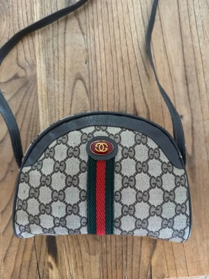 Gucci axelväska med GG-mönster (sällsynt äkta) från 1980 - Väldigt sällsynt och vintage Äkta Gucci väska från 1980-1990 talet som jag fick av min farmor 2018. Den är väldigt bra bevarad och är i helt nytt skick, priset kan diskuteras! Finns inget kvitto låda, de som är på bilden medföljer. Jag vet inte priset jag ska sälja det för så 4000 börjar vi på nån gå ner!