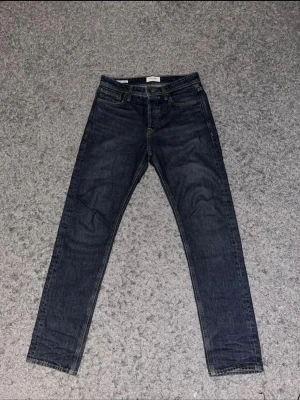 Jack & Jones - Säljer ett par klassiska mörkblå jeans från Levi's med raka ben och fem fickor. Jeansen har en snygg, enkel design och är perfekta för en avslappnad stil. Tillverkade i bomull för en skön känsla hela dagen.