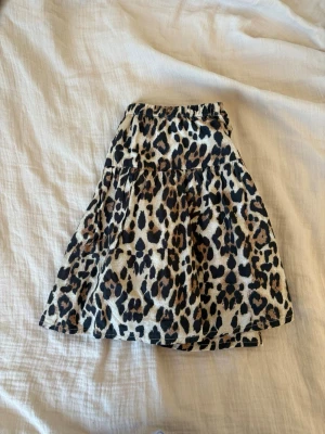 Leopardmönstrad kortkjol med volang - Snygg kortkjol med leopardmönster och volang. Kjolen har resår i midjan för en bekväm passform och är perfekt för dig som vill sticka ut. Materialet känns mjukt och lätt, vilket gör den skön att bära hela dagen.