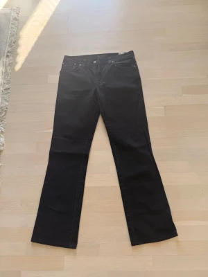Nudie slim jim jeans - Nudie Jeans svarta jeans – premium denim Stilrena svarta jeans från Nudie Jeans med klassisk design och bekväm passform. Tillverkade i kvalitetsdenim med lätt stretch och snygga diskreta detaljer. Perfekta både till vardag och mer uppklädda outfits.  * Märke: Nudie Jeans * Färg: Svart * Passform: Slim/regular fit * Material: Stretchdenim * Skick: Mycket fint skick  Klassisk premiummodell från Nudie med hög kvalitet och tidlös stil.