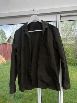 Olivgrön skjorta från Matinique - Stilren olivgrön skjorta från Matinique med klassisk krage och bröstficka. Skjortan har lång ärm och knäppning framtill. Perfekt för dig som gillar en enkel men snygg look.
