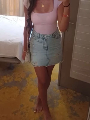 Ljusrosa topp med fyrkantig ringning - Snygg ljusrosa topp med fyrkantig ringning och korta ärmar. Toppen är figurnära och tillverkad i mjuk bomull, perfekt för en trendig och enkel look. Passar till både jeans och kjol för en fräsch stil.