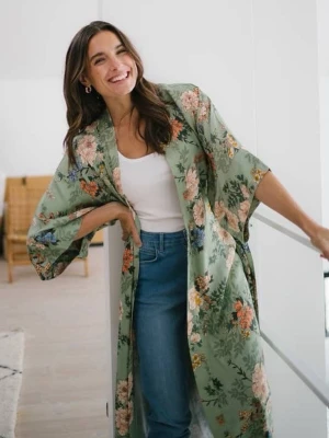 Nyskick! Grön blommig kimono från indiska  - Snygg grön kimonomo med blommigt mönster i rosa, orange, blått och vitt. Långa, vida ärmar och knytskärp i midjan. Fickor i sidorna. Perfekt för chill dagar hemma eller när du vill känna dig extra lyxig på morgonen. Materialet är glansig mjuk viskos. Provad och har sedan blivit hängande i garderoben. Nypris var runt 900;- stl S/M ganska rymlig modell