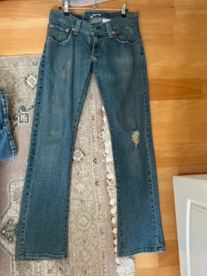 Levi's vintage limited edition low waisted jeans - Säljer ett par klassiska blå jeans från Levi's med snygga slitningar på framsidan. Passar bra S-M storlek.
