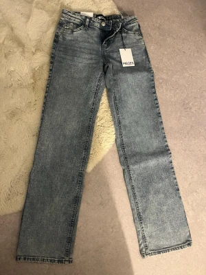 Ljusblå raka jeans från Pieces - Säljer ett par ljusblå raka jeans från Pieces, modell PCBELLA LW STRAIGHT. Jeansen har klassisk femficksdesign, normal midja och är i ett mjukt denimtyg. Perfekta för en avslappnad och trendig look.