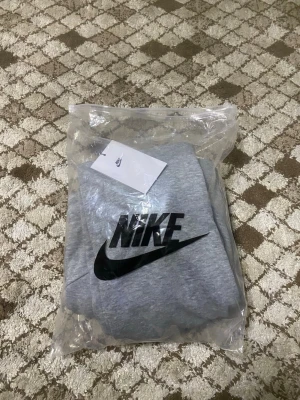 Gråa mjukisbyxor från Nike - Snygga gråa mjukisbyxor från Nike med klassisk logga på benet. Byxorna har dragsko i midjan och raka ben, perfekta för en avslappnad stil. Tillverkade i mjukt material som känns skönt mot huden.
