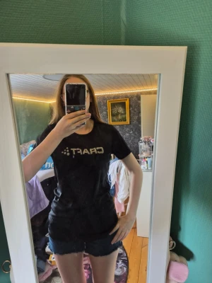 Svart t-shirt från Craft i M - Svart t-shirt från Craft med logga framtill. Modellen är figurnära med rund hals och korta ärmar. Perfekt för dig som gillar en sportig och enkel stil. Materialet känns mjukt och följsamt mot kroppen.