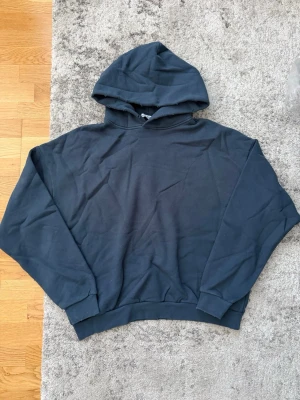 Mörkblå hoodie från Acne Studios - Snygg mörkblå hoodie från Acne Studios med tryck på ryggen där det står 'Acne Studios STOCKHOLM 1996'. Klassisk modell med huva och ribbade muddar. Perfekt för en avslappnad och trendig stil.