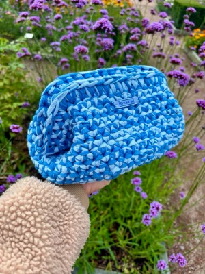 Blå virkad necessär By Elin - Modell AGNES - Mixed blue - Superfin handgjord necessär i blått och ljusblått från By Elin. Väskan är virkad i ett mjukt tygmaterial och har en rektangulär form och öppnas och stängs med en metallclips. Perfekt för att förvara småsaker eller smink i väskan.