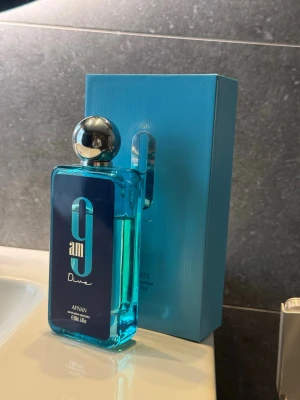 Afnan 9am Dive Eau de Parfum - Afnan 9am Dive är en parfym med en modern, rektangulär flaska i klar blå färg och en silverfärgad rund kork. Flaskan har en stilren design med blå etikett och vita detaljer. Kommer i matchande blå kartong.