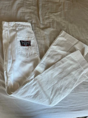Vita jeans från Sgt Pepper - Snygga vita jeans från Sgt Pepper med klassisk femficksmodell och patch med brittiska flaggan på bakfickan. Perfekta för dig som vill sticka ut med en fräsch och stilren look. Står ingen storlek men passar mig som bär xs