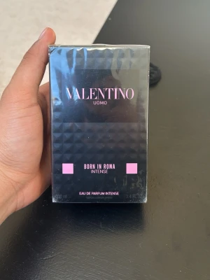 Valentino Uomo Born In Roma Intense - Valentino Uomo Born In Roma Intense är en lyxig parfym i en svart, fyrkantig förpackning med rosa detaljer. Kartongen har ett coolt pyramidmönster och rymmer 100 ml Eau de Parfum Intense. Perfekt för dig som gillar exklusiva och moderna dofter.