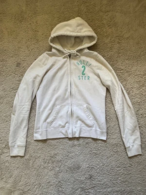 Zip up Hoodie Hollister  - Zip up Hoodie ifrån Hollister i storlek S, något nopprig och missfärgad längst ner vid ärmarna! 