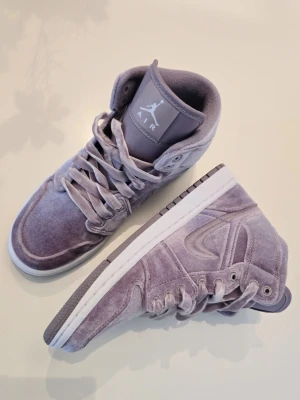 Air Jordan 1 Mid Velvet lila NYA! - Unika Air Jordan 1 Mid sneakers i lila sammet med matchande skosnören och vit sula. Klassisk siluett med rund tå och högt skaft. Swoosh på sidan och Jumpman-logga på plösen. Perfekta för dig som vill sticka ut med en lyxig och trendig look. Helt nya endast testad.