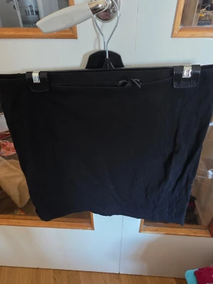 Svart kortkjol från H&M Basic - Enkel svart kortkjol från H&M Basic med dragsko i midjan. Kjolen har en rak passform och är tillverkad i mjukt material som känns bekvämt mot huden. Perfekt för en stilren och avslappnad look.