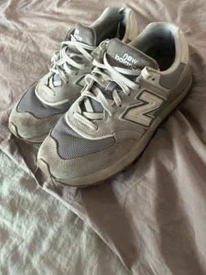Grå New Balance 990 sneakers - Snygga grå New Balance 990 sneakers med klassisk siluett. Skorna har meshpaneler och mockadetaljer, samt den ikoniska N-loggan på sidan. Perfekta för dig som gillar streetwear och sportig stil. Sköna snörningar och dämpad sula för extra komfort.