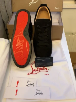 Svarta designer sneakers - Snygga svarta sneakers från Christian Loubitins. Svart sko med röd sula, kommer med låda, kort, och påse. Lyxiga svarta designer sneakers som passar perfekt med en stilig outfit till sommaren! 