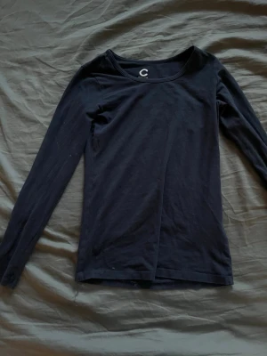 Svart långärmad topp från Cubus - En svart långärmad topp från Cubus i mjuk bomull. Enkel och stilren design med rund halsringning och tight passform. Perfekt att matcha med jeans eller kjol för en clean look. Storleken är xxs men passar super bra på xs/s