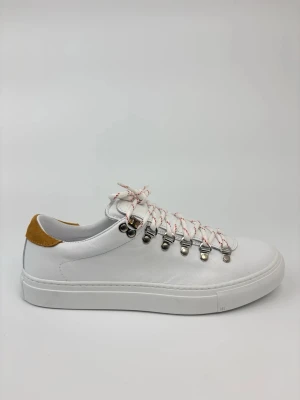 Vita Diemme sneakers med färgade snören - Stilrena vita sneakers i läder med unika rödvita snören och metallöglor. Skon har en tjock vit sula och en kontrastdetalj i senapsgult på hälen. Perfekt för dig som gillar en clean look med en twist.