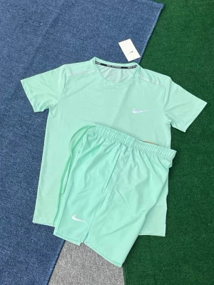 Mintgrönt träningsset från Nike - Säljer ett fräscht mintgrönt träningsset från Nike med t-shirt och shorts. Båda plaggen har den klassiska vita Nike-loggan. Materialet är lätt och andas, perfekt för träning eller sportaktiviteter. T-shirten har rund hals och shortsen har resår i midjan.
