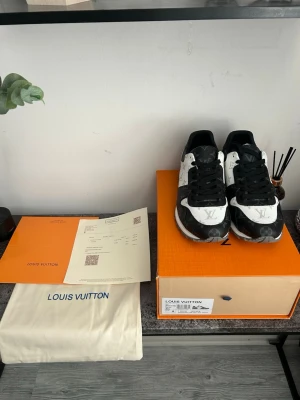 Louis Vuitton svartvita sneakers - Louis Vuitton sneakers i svart och vitt med klassiskt monogrammönster. Skorna har svarta snören, rund tå och är tillverkade i läder och canvas. Snygg kontrast mellan färgerna och tydliga LV-detaljer gör dem till ett statement i varje outfit.