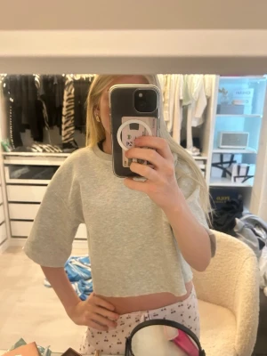 Grå croppad t-shirt med vida ärmar - Superenkel och snygg grå croppad t-shirt med vida, korta ärmar. Perfekt till jeans eller mjukisbyxor för en chill look. Mjuk och skön bomullskänsla, passar dig som gillar avslappnad stil. SWEATSHIRT SOM ÄR AVKLIPPT !